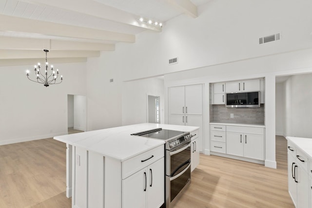 kitchen with pendant lighting, white cabinets, appliances with stainless steel finishes, a center island, and beamed ceiling