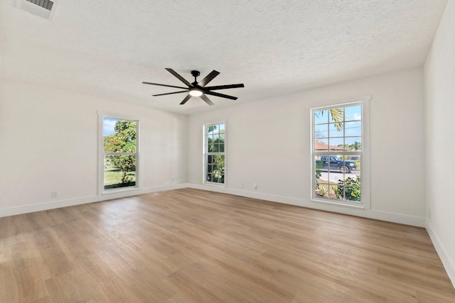 spare room with light wood-type flooring, ceiling fan, and a textured ceiling