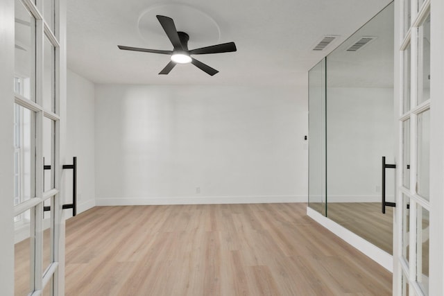 empty room with ceiling fan, french doors, and light wood-type flooring