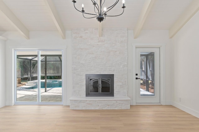 unfurnished living room with light wood-type flooring, a fireplace, beamed ceiling, and a notable chandelier