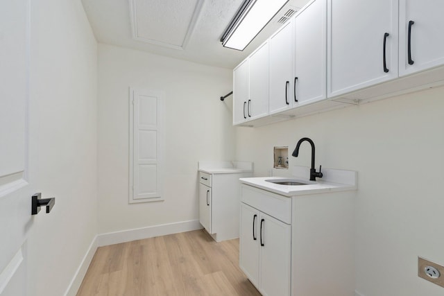 laundry area featuring sink, hookup for a washing machine, light hardwood / wood-style flooring, electric dryer hookup, and cabinets