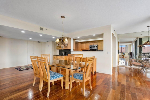 dining area featuring dark hardwood / wood-style floors, an inviting chandelier, and a textured ceiling