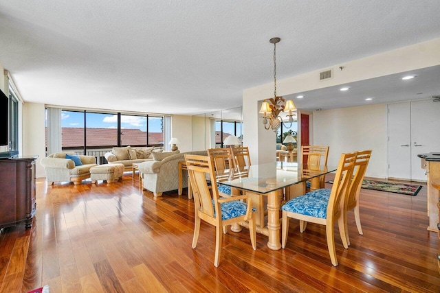 dining area with a textured ceiling, an inviting chandelier, a wall of windows, and wood-type flooring