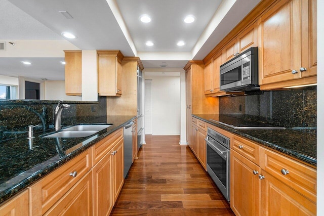 kitchen featuring appliances with stainless steel finishes, dark stone countertops, decorative backsplash, and sink