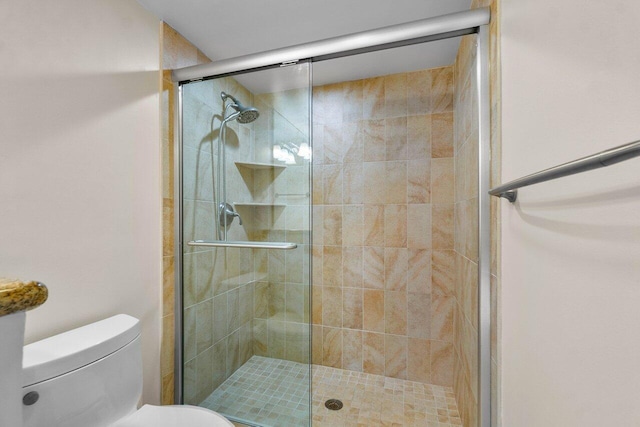 bathroom featuring toilet and a shower with shower door