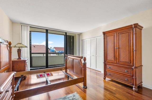 bedroom with floor to ceiling windows, hardwood / wood-style flooring, and a closet