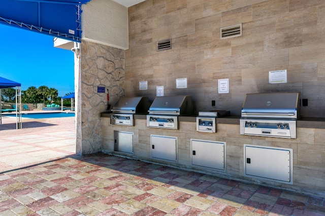 view of patio with exterior kitchen, a grill, and a community pool