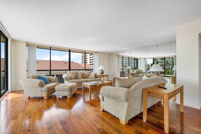 living room featuring a healthy amount of sunlight, wood-type flooring, floor to ceiling windows, and a textured ceiling