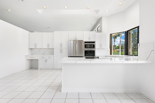 kitchen with white cabinetry, appliances with stainless steel finishes, kitchen peninsula, and light tile patterned floors