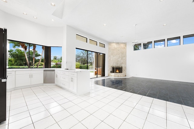 kitchen with white cabinetry, light tile patterned floors, kitchen peninsula, dishwasher, and a fireplace