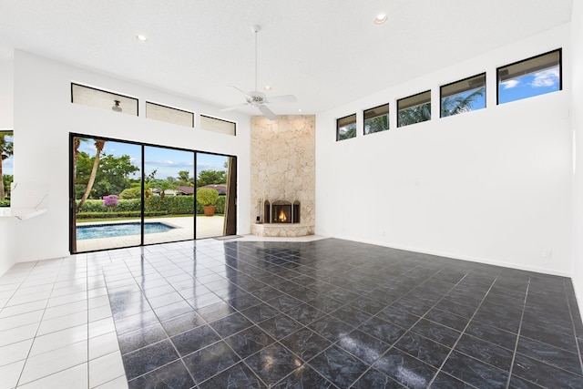 unfurnished living room with a towering ceiling, a fireplace, and ceiling fan