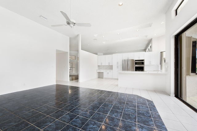 unfurnished living room with ceiling fan and a high ceiling