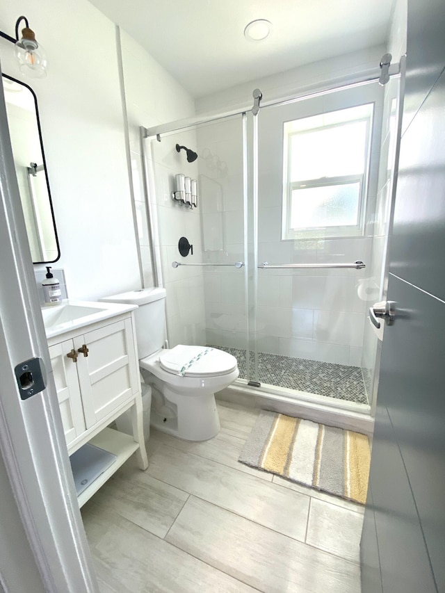 bathroom with toilet, vanity, and a shower with door