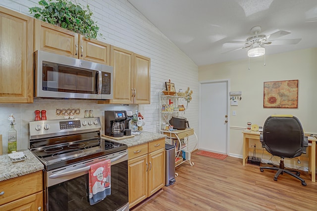 kitchen featuring light wood-type flooring, stainless steel appliances, lofted ceiling, and light stone counters