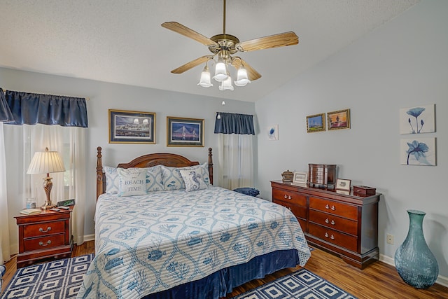 bedroom featuring ceiling fan, dark wood-type flooring, a textured ceiling, and lofted ceiling