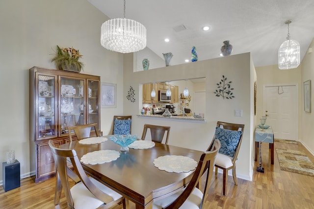 dining area with a chandelier, light hardwood / wood-style floors, and a towering ceiling