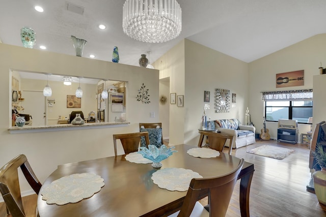 dining room featuring hardwood / wood-style floors, lofted ceiling, and an inviting chandelier