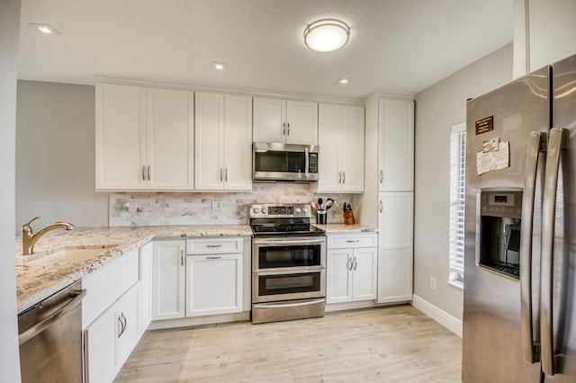 kitchen with white cabinetry, sink, light stone countertops, and appliances with stainless steel finishes