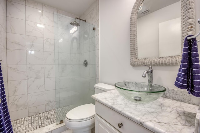 bathroom with a tile shower, vanity, and toilet