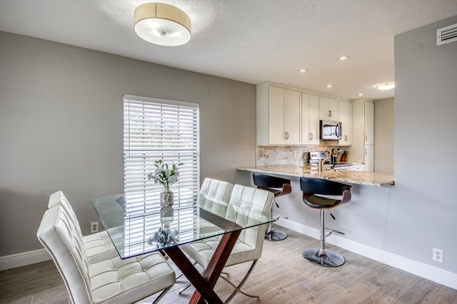 dining area featuring sink and light hardwood / wood-style floors