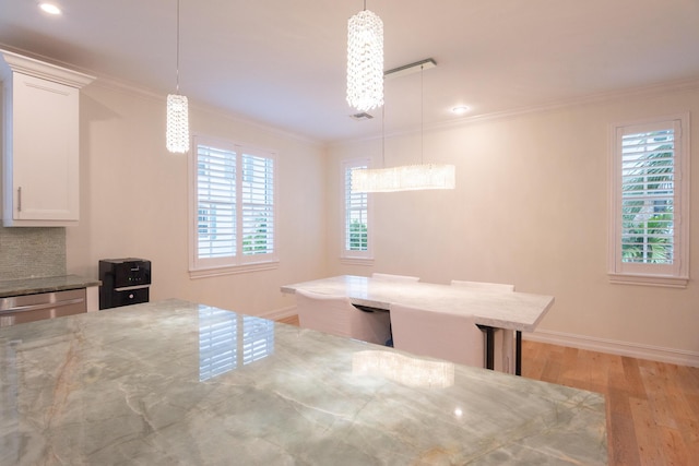 unfurnished dining area featuring ornamental molding and light hardwood / wood-style floors