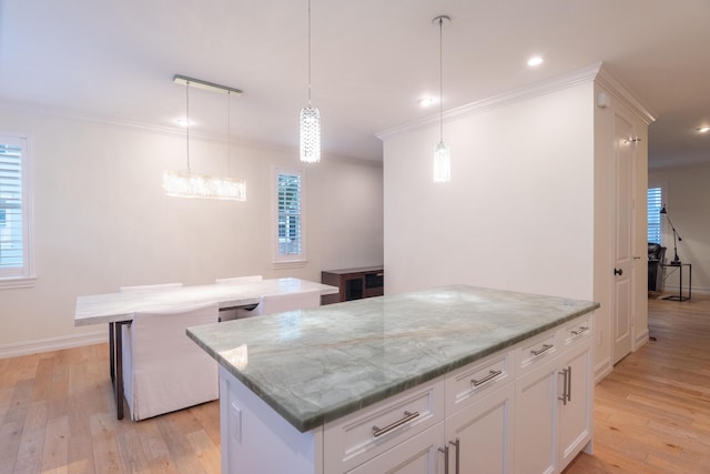 kitchen with white cabinetry, light stone counters, decorative light fixtures, and a center island