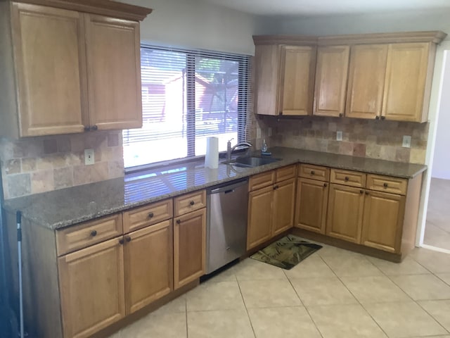 kitchen featuring sink, light tile patterned floors, dark stone countertops, dishwasher, and decorative backsplash