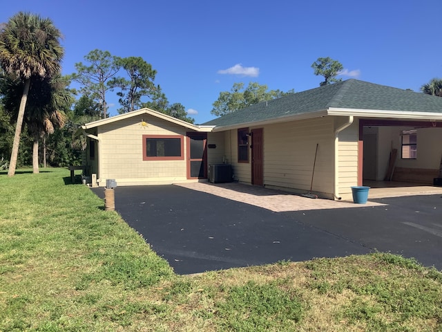 ranch-style home with central air condition unit and a front yard