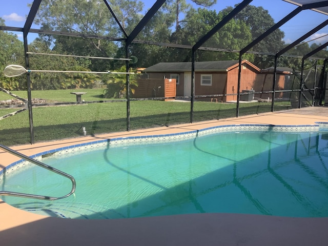 view of pool with a lanai and a lawn