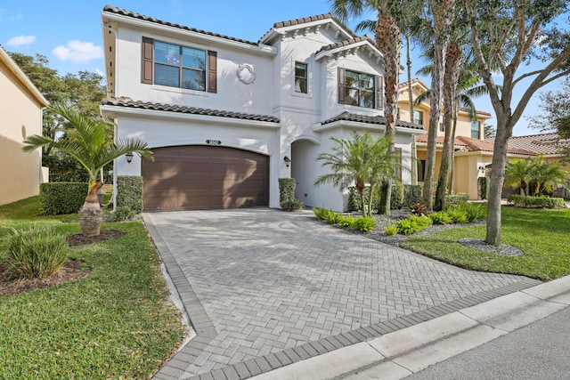 mediterranean / spanish home featuring a garage and a front yard