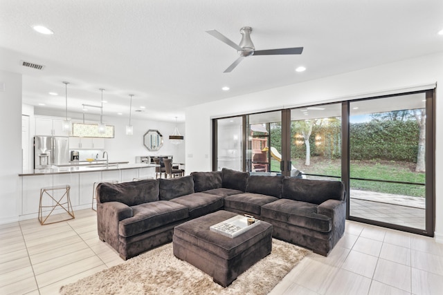 living room featuring light tile patterned floors, sink, a textured ceiling, and ceiling fan