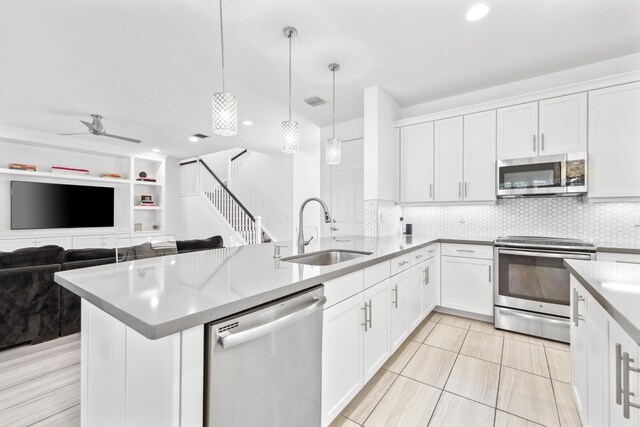 kitchen featuring stainless steel appliances, pendant lighting, white cabinets, and sink