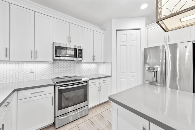 kitchen featuring stainless steel appliances, decorative backsplash, and white cabinets