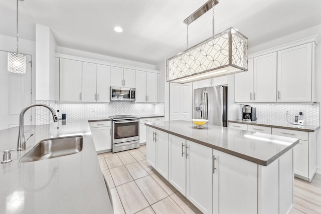 kitchen with sink, stainless steel appliances, hanging light fixtures, and white cabinets