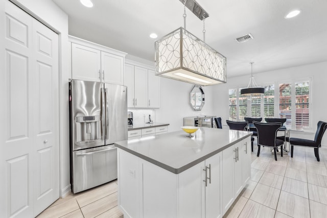 kitchen featuring stainless steel refrigerator with ice dispenser, tasteful backsplash, a kitchen island, pendant lighting, and white cabinets