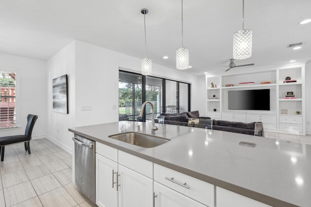 kitchen featuring pendant lighting, built in features, white cabinetry, sink, and stainless steel dishwasher