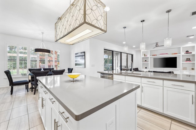 kitchen with dishwasher, pendant lighting, sink, a large island, and white cabinets