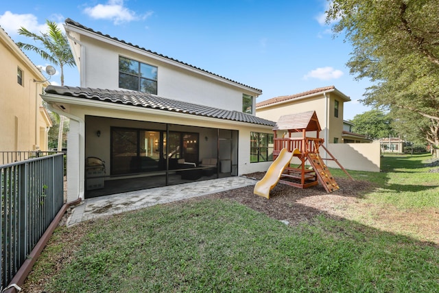 back of house featuring a playground and a lawn