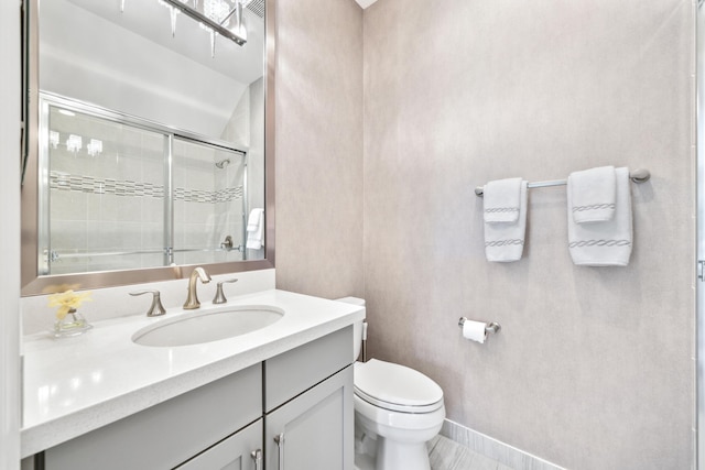 bathroom featuring vanity, a shower with door, and toilet