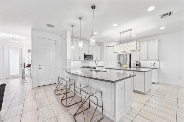 kitchen with stainless steel appliances, hanging light fixtures, and white cabinets