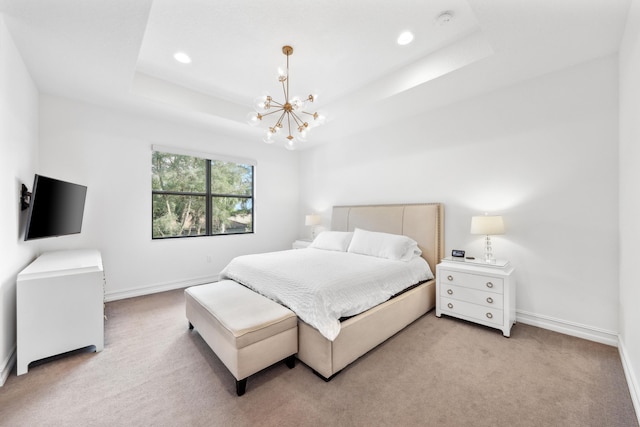 carpeted bedroom with a notable chandelier and a tray ceiling