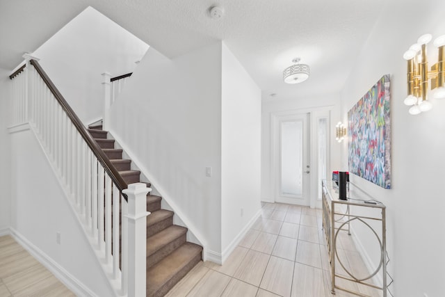 foyer entrance with a textured ceiling and light tile patterned flooring