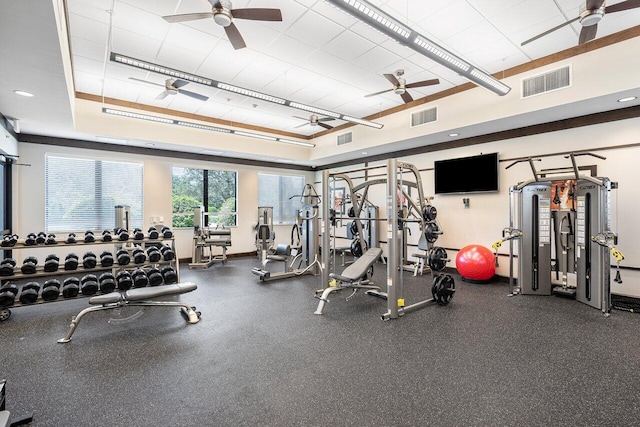 workout area featuring a tray ceiling and ceiling fan