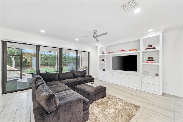 tiled living room with built in shelves, ceiling fan, and a textured ceiling