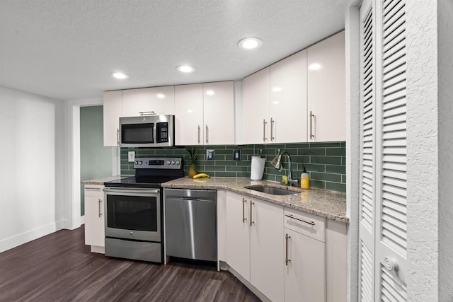 kitchen with white cabinets, stainless steel appliances, decorative backsplash, sink, and dark hardwood / wood-style floors