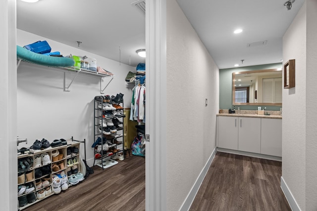 walk in closet with dark wood-type flooring