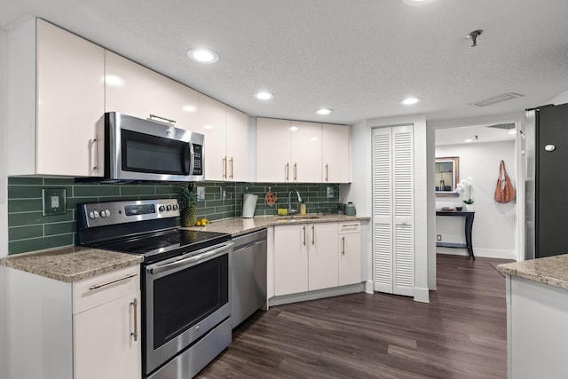 kitchen featuring tasteful backsplash, white cabinets, and appliances with stainless steel finishes