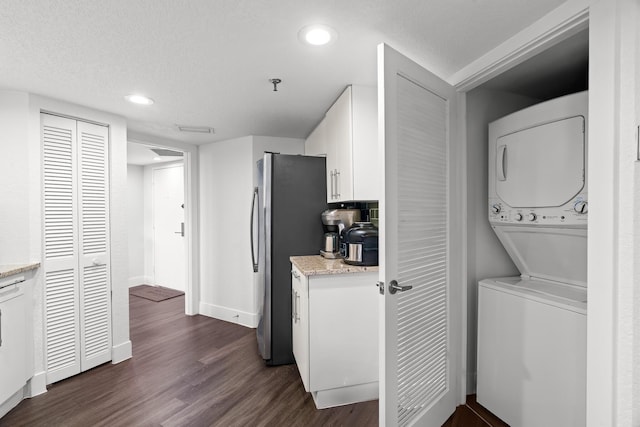 laundry room with a textured ceiling, stacked washer and clothes dryer, and dark hardwood / wood-style floors