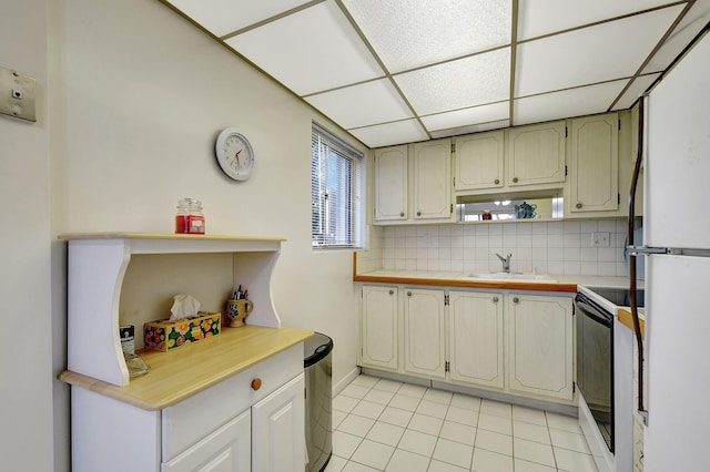 kitchen featuring decorative backsplash, sink, white appliances, a paneled ceiling, and light tile patterned floors