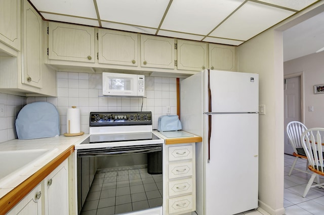 kitchen with white appliances, sink, backsplash, tile countertops, and light tile patterned flooring